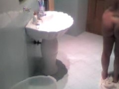 Brunette gets naked in the bathroom and filmed on a spy cam