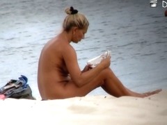 Beach nudist woman has covered her body with newspaper